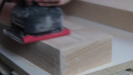 Finish-sanding-the-wood-filler-on-wooden-floating-shelves-in-preparation-to-be-stained-and-hung-in-a-remodeled-bathroom