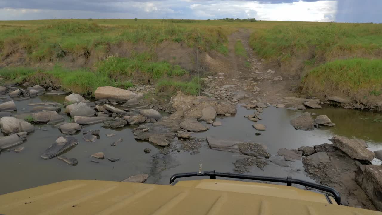 un jeep de safari conduce a través de un río seco