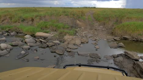 a safari jeep drives through a drying river