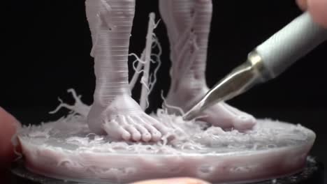detailed artistry in progress: a close-up of handcrafted feet sculpture with intricate textures and materials being perfected by a skilled artisan