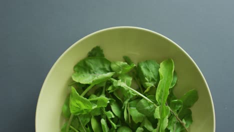 Video-of-close-up-of-bowl-of-fresh-salad-leaves-on-grey-background