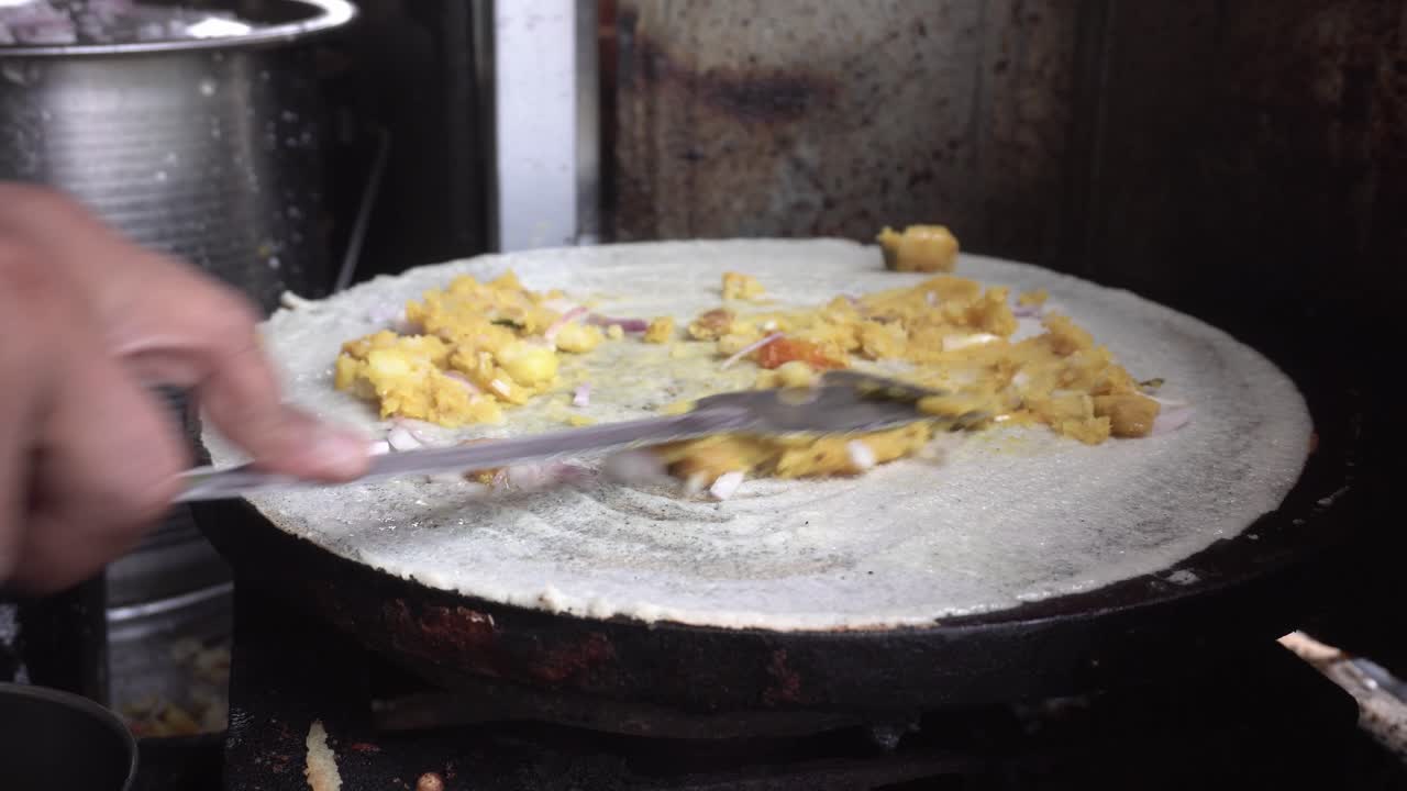 un fabricante de comida callejera prepara la comida del sur de la india dhosa