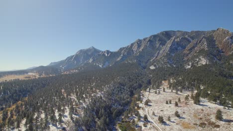 aerial drone shot of the flatiron mountains covered in snow in boulder, colorado, usa on a fall day