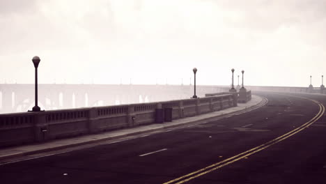 foggy road alongside bridge with lamp posts in a serene urban landscape