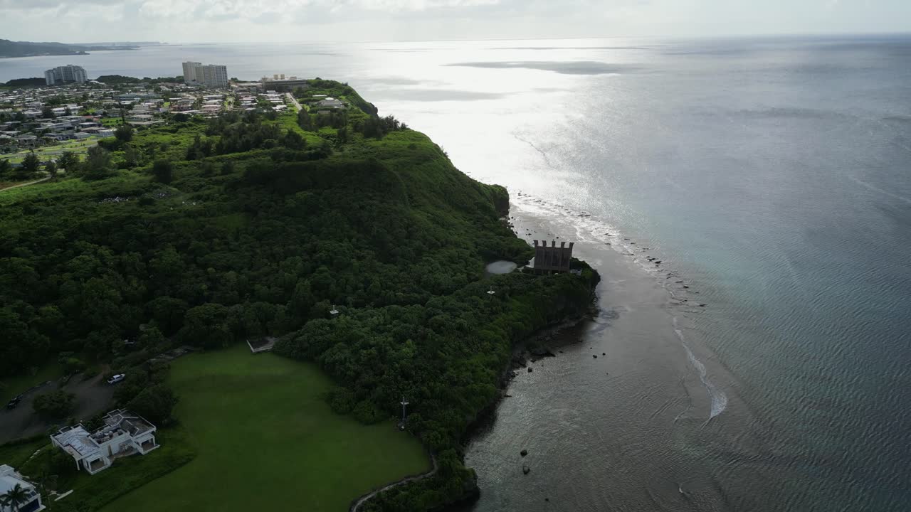 Stunning aerial overview of lush hilltop and quaint chapel overlooking ocean coast during sunset at Tamuning, Guam, USA