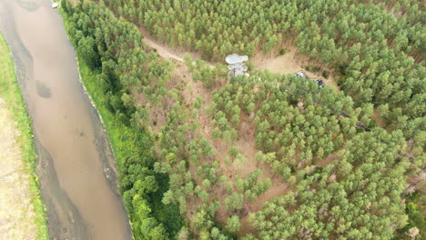 Merkine-observation-tower-surrounded-by-dense-forest-and-river-on-side,-aerial-view