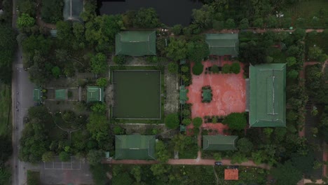 aerial top down tracking shot of ancient buddhist temple, gardens and street with traffic in south vietnam