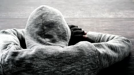 person in a gray hoodie lying on a wooden surface