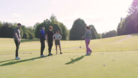 Golf players playing golf together, hitting the ball with club on a golf course on a sunny day