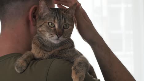 man stroking a cat on his shoulder.