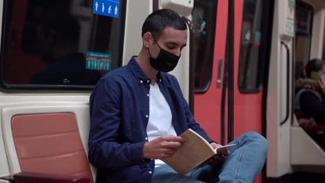 Unrecognizable-passenger-in-mask-reading-copybook-on-subway