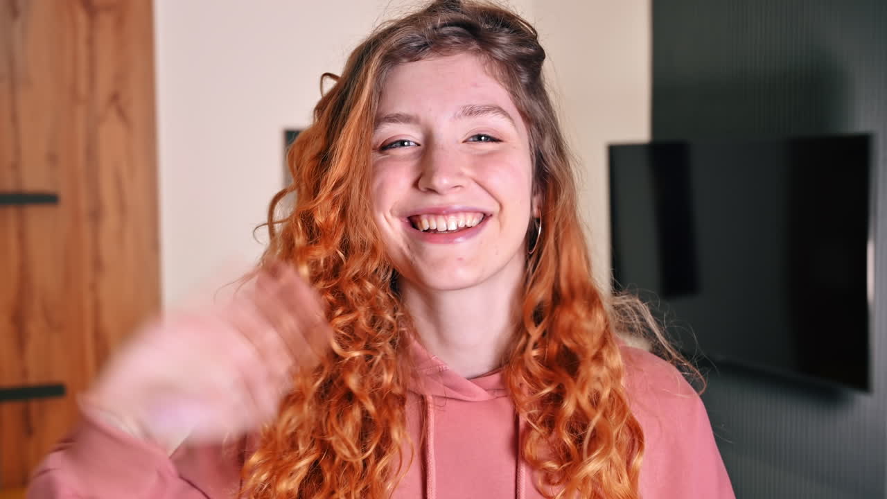 Portrait of young girl with ginger hair waving hand. Working from home