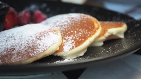 delicious pancakes with powdered sugar, chocolate sauce, and berries
