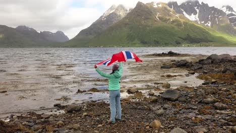 woman with a waving flag of norway on the background of nature