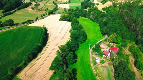 aerial-drone-shot-over-farmland-and-forest-in-summer,-4k