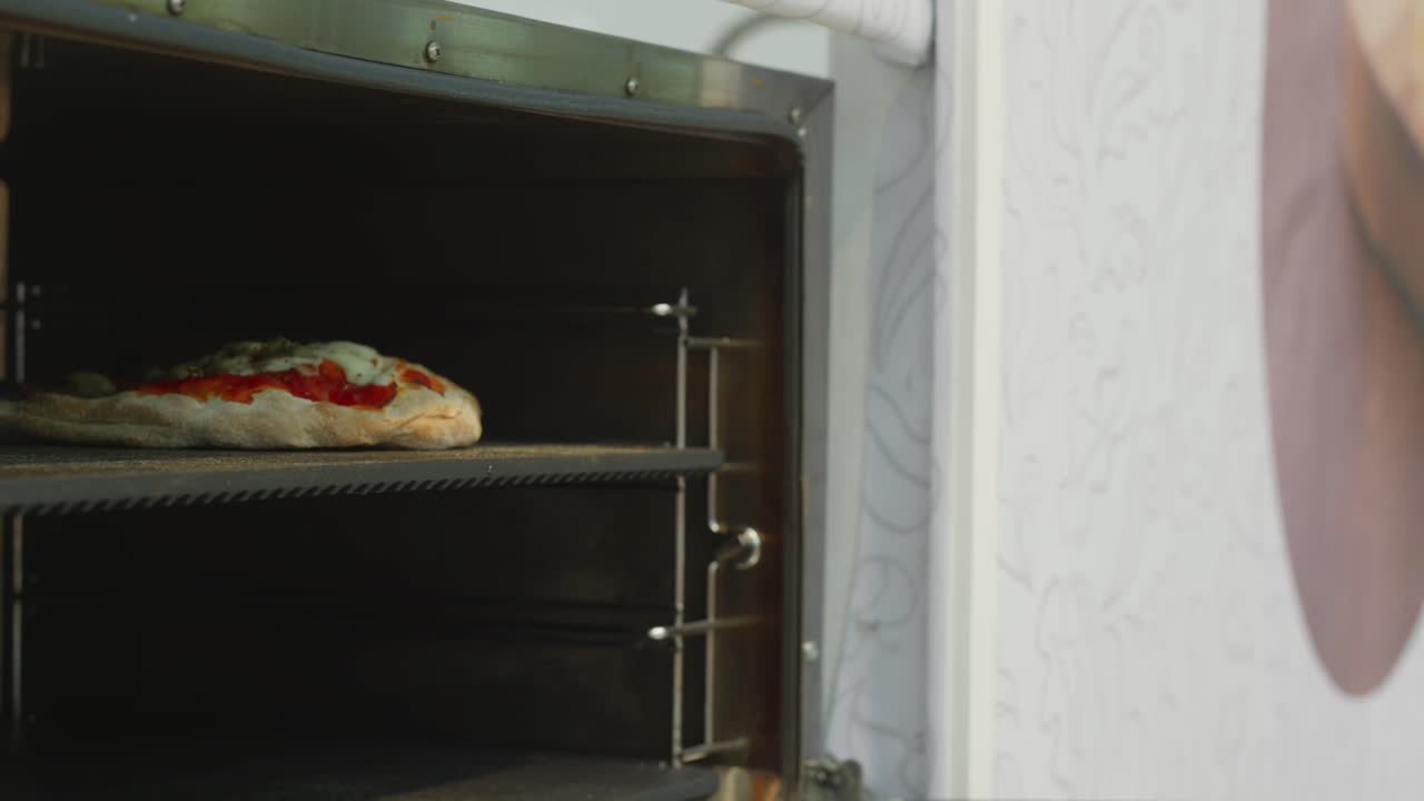 Freshly baked focaccia pizza being removed from the oven by a chef wearing gloves, Italy.