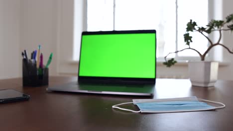 green screen laptop computer sitting on a home work desk.