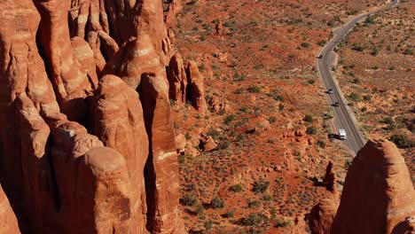 aerial of dramatic red rock formations and a winding road in moab, utah, usa