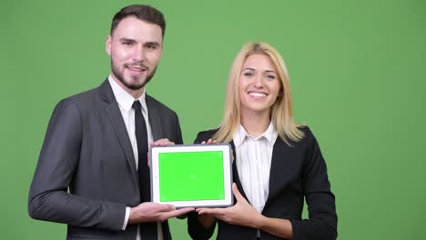 young happy business couple showing digital tablet together