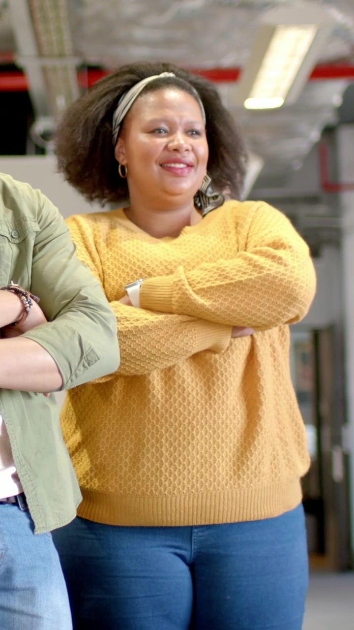Vertical video: Hearing peer joke, woman in mustard top laughing, leaning in corridor, smartwatch