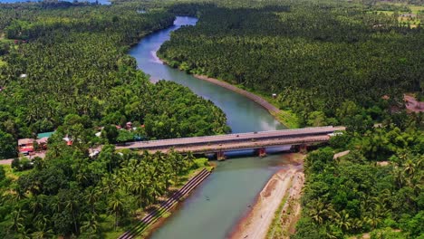 aerial view of a bridge over flowing river among thicket woods in saint bernard, southern leyte in the philippines