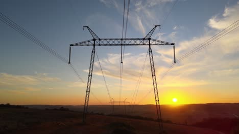 dark silhouette of high voltage tower with electric power lines at sunrise. transmission of electric energy concept