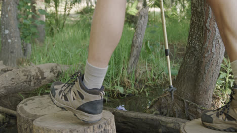 Low-section-of-african-american-man-hiking-with-trekking-poles-in-forest,-slow-motion