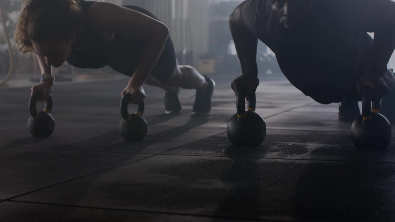 Atleti che eseguono flessioni con kettlebell in una palestra moderna