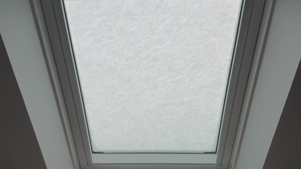 Snow-covered skylight on a winter day viewed from indoors with soft natural light coming through