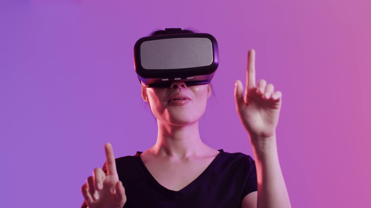 donna asiatica felice che usa un auricolare vr e tocca uno schermo virtuale su sfondo viola, slow motion