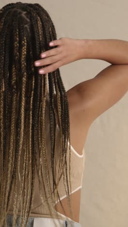 rear view studio shot of young woman with long braided hair feeling softness after hair care product