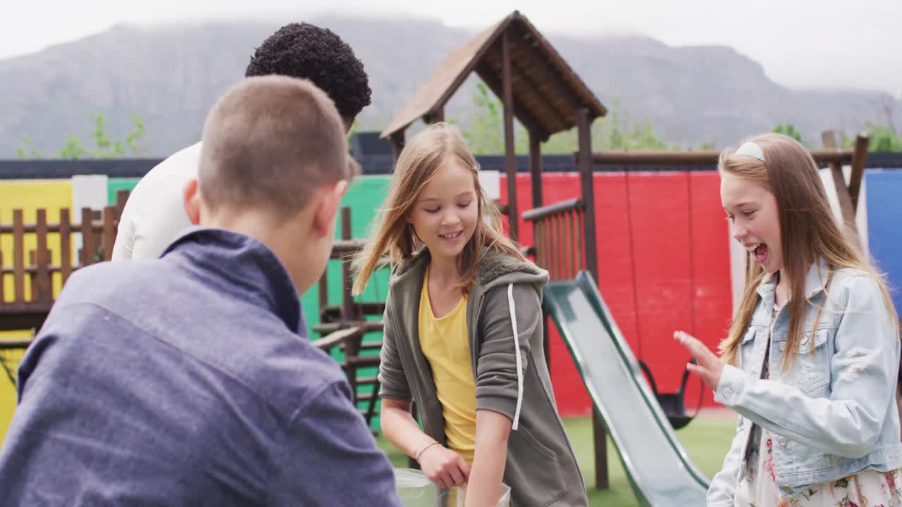 다양한 여성 교사 와 행복 한 학교 학생 들 이 학교 놀이터 에서 가방 을 가지고 함께 청소 하고 있다