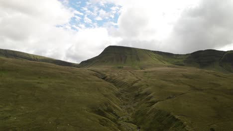 Idyllic-Brecon-beacons-national-park-llyn-y-fan-fach-mountain-range-aerial-rising-view-above-rolling-valley