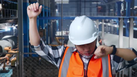 close up of asian male engineer with safety helmet screaming goal and dancing celebrating while standing in factory manufacture of wind turbines