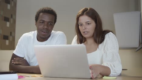 couple of startup managers sitting at table with laptop