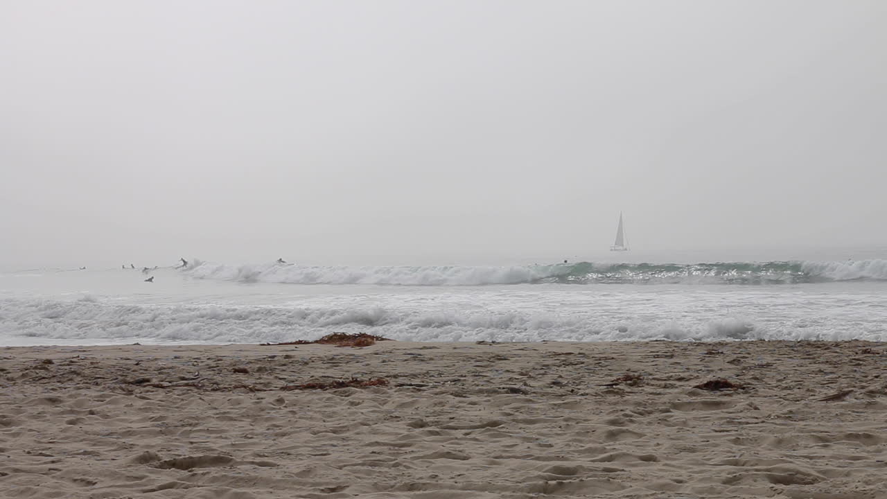보행자가 산책하고 서퍼가 파도를 칠 때 베니스 해변 위의 해양층