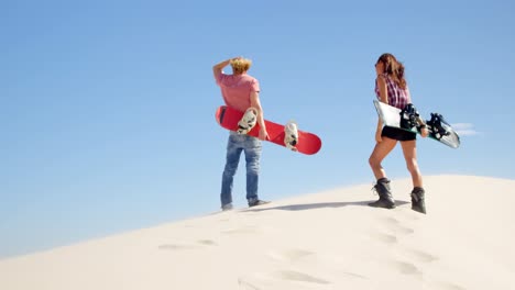 Pareja-Con-Tablas-De-Arena-Mirando-A-Lo-Lejos-En-El-Desierto-4k