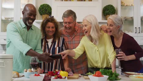 animation of happy diverse female and male senior friends preparing meal, using smartphone