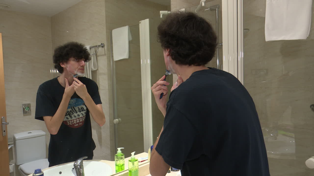Man shaving in a hotel bathroom
