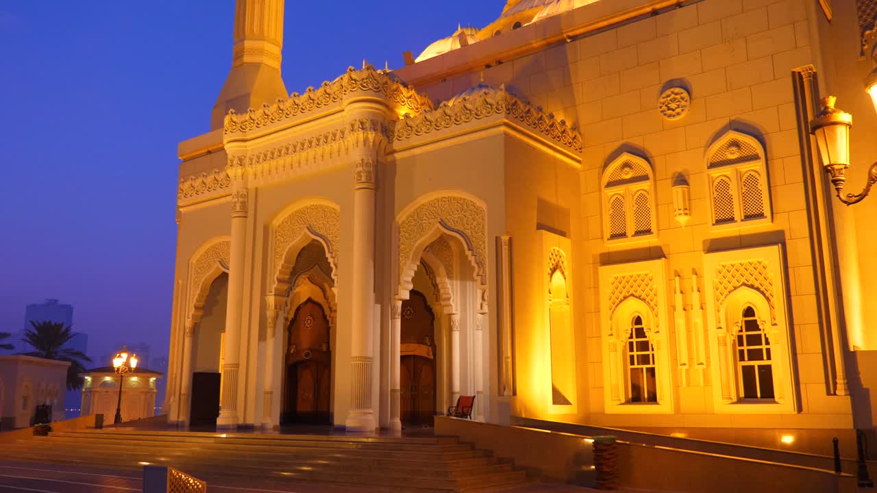 dolly disparó a la mezquita al noor en la ciudad de sharjah, uae. vista nocturna de la mezquita iluminada. adoración islámica. luces doradas de linterna. color cobalto del cielo.