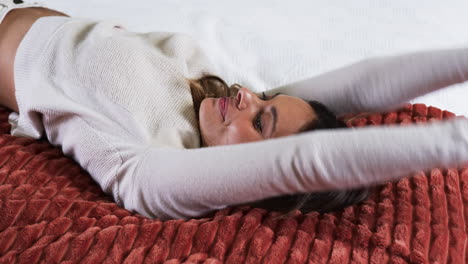 relaxing at home, woman smiling joyfully on cozy red blanket