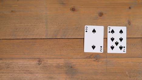 a person laying out a deuce on a wooden table to educate the viewer on how to play poker