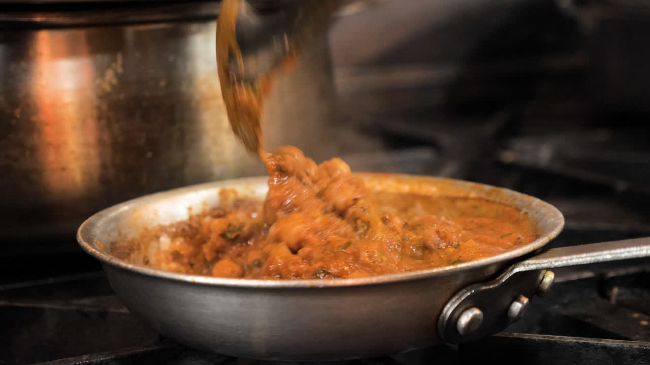 el chef remueve el auténtico chana masala en la cocina de un restaurante comercial, el control deslizante en cámara lenta cierra hd
