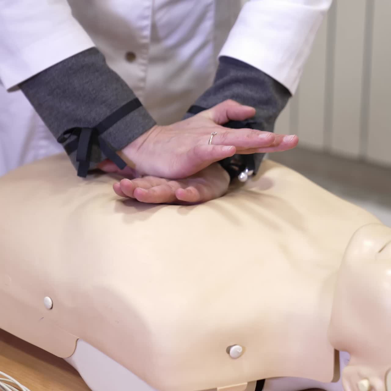 CPR First Aid Training. Demonstrating chest compressions on CPR doll in the class