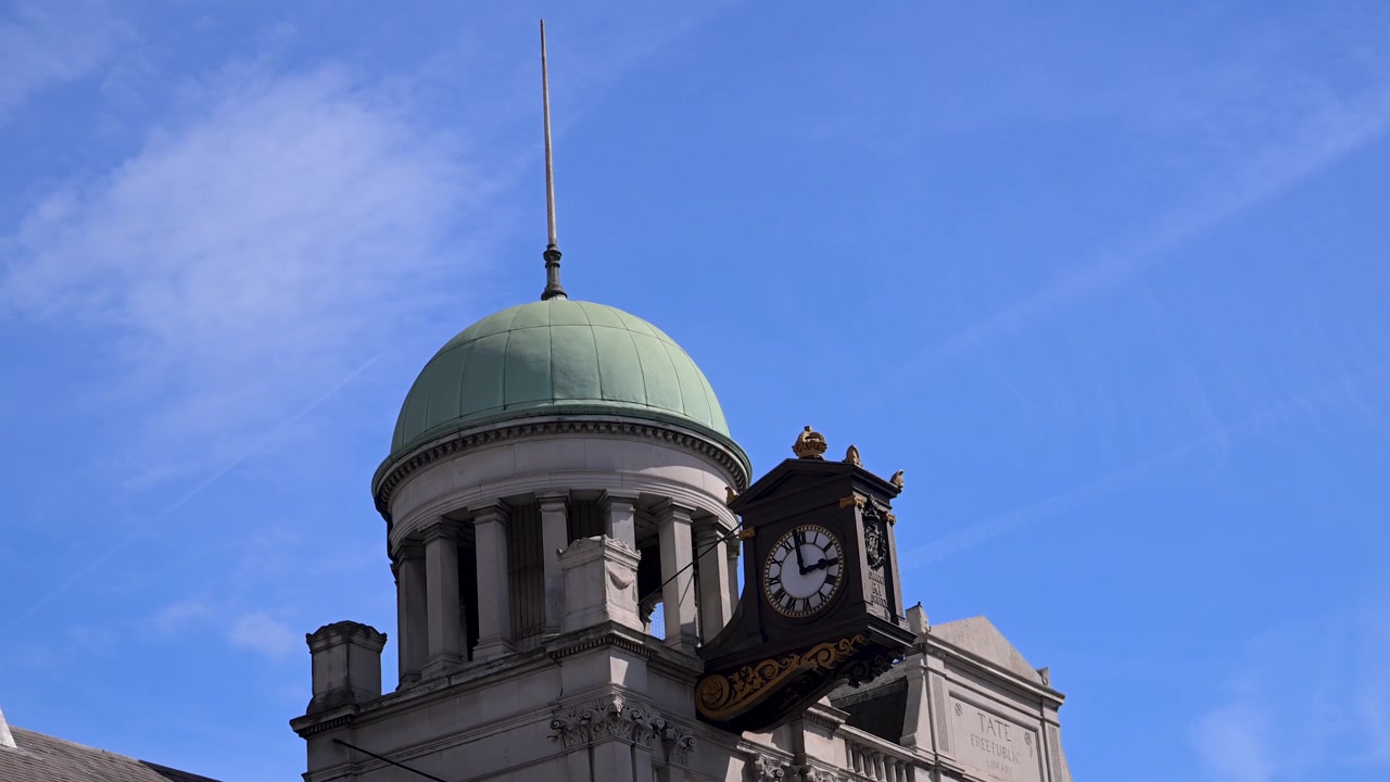 La Biblioteca Streatham Tate, catalogada como Grado II, presenta una destacada torre del reloj bajo un cielo azul claro. Ideal para proyectos con temática de historia o arquitectura