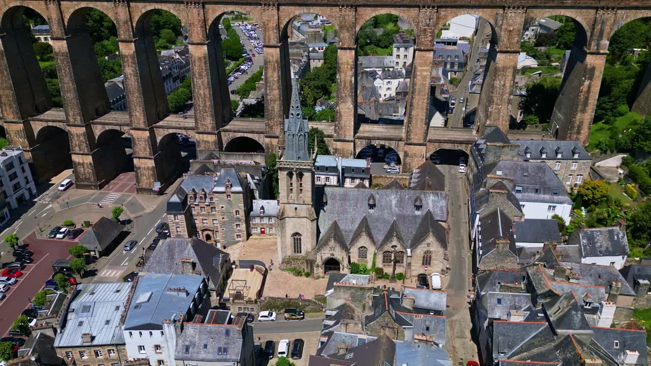 Lateral drone shot of Saint-Melaine Church and Morlaix Viaduct in Brittany, showing the historic town and stone structures