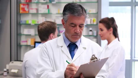 senior pharmacist writing on clipboard