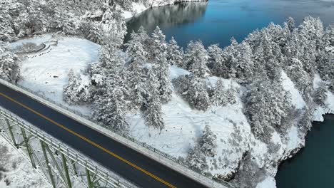 rising aerial view revealing deception pass bridge empty with snow covering the surrounding land