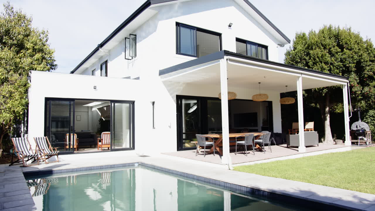 Modern white house with swimming pool and outdoor dining area in backyard