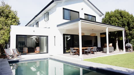 modern white house with swimming pool and outdoor dining area in backyard